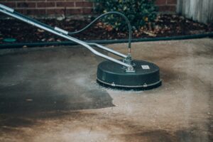 Power washing equipment cleaning driveway surface, showcasing effective removal of dirt and grime in Florida's humid climate.