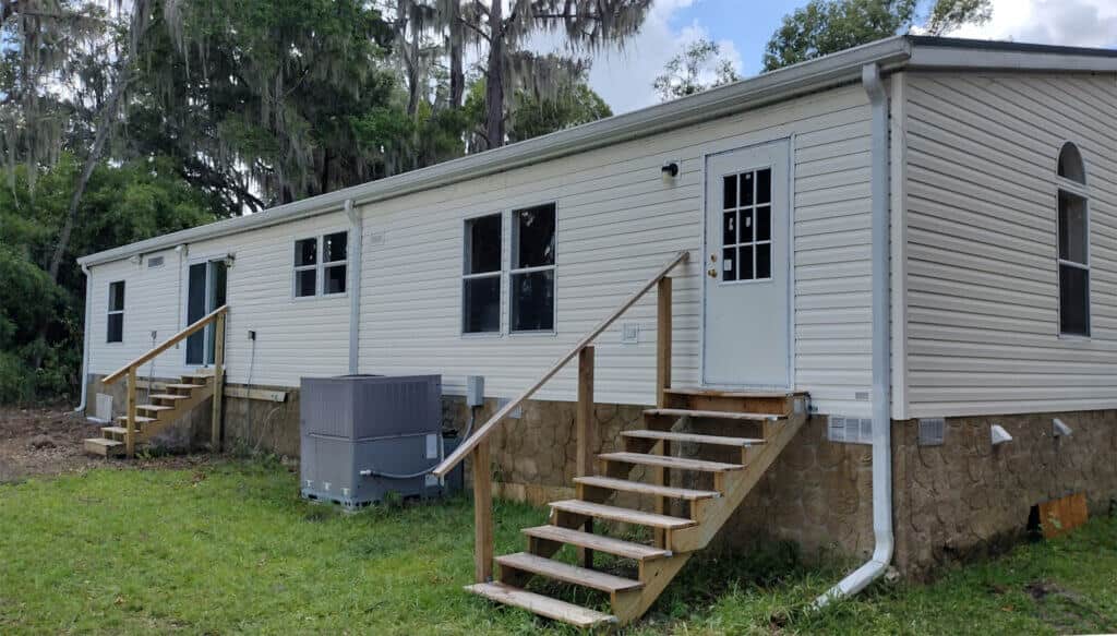 Exterior view of a clean, white mobile home with horizontal vinyl siding