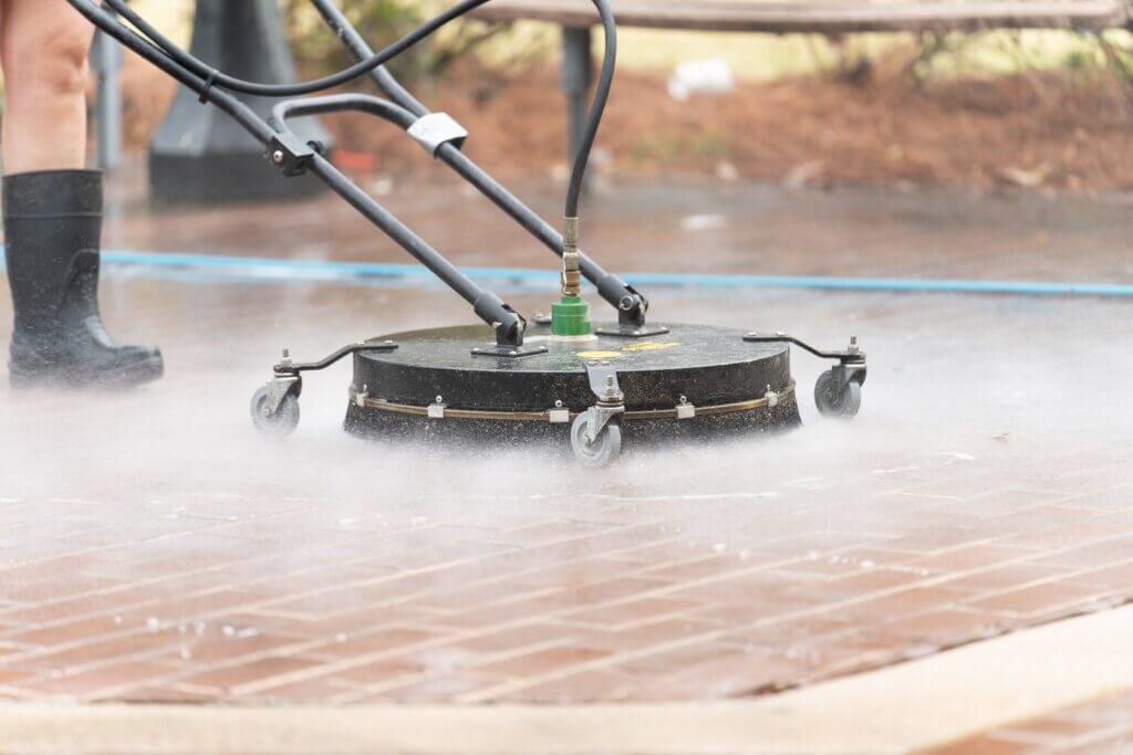 A professional surface cleaner attachment being used by Starr’s & Stripes PowerWash to deep clean a brick paver patio in Ocala.
